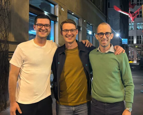 Three young urologists standing next to each other with their hands on each other's shoulders