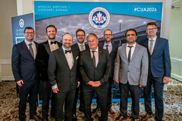 Group of men in suits standing in front of an event poster
