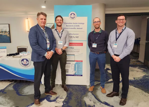 4 men standing next to a vertical event poster